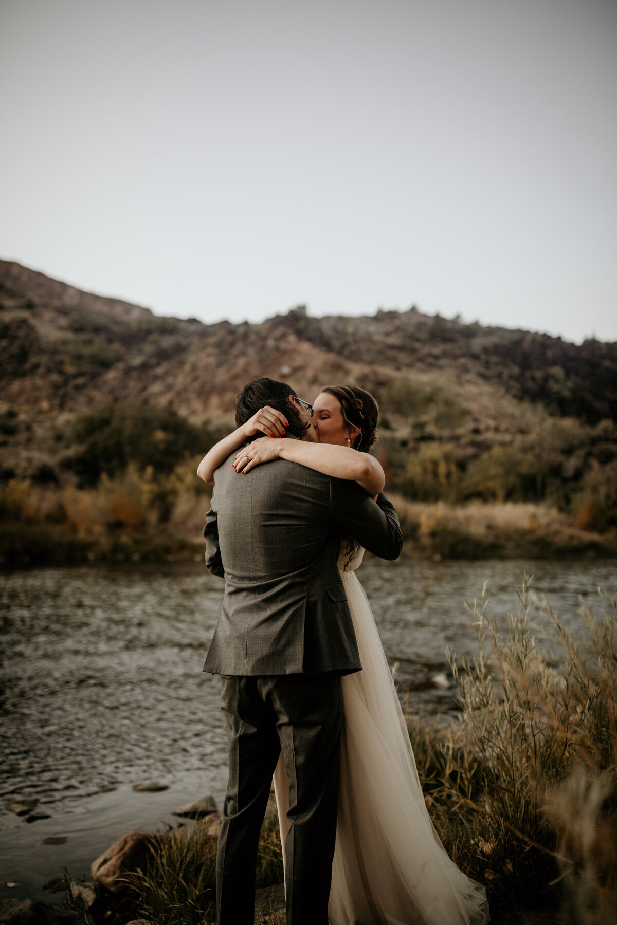 bride and groom hugging after vows by a river