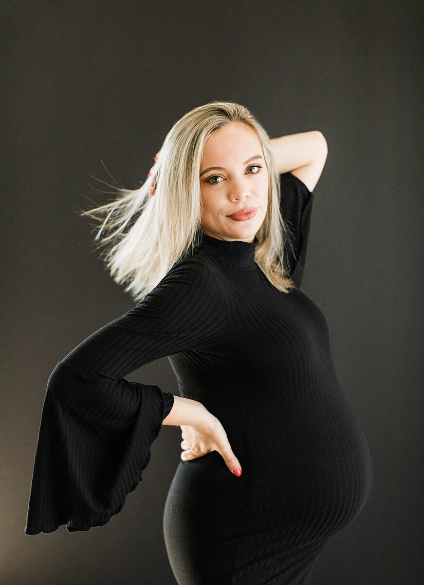 dramatic maternity portrait of pregnant woman in black dress with her hair blowing in the wind
