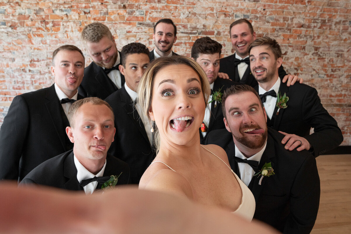 Bride takes selfie with groomsmen.