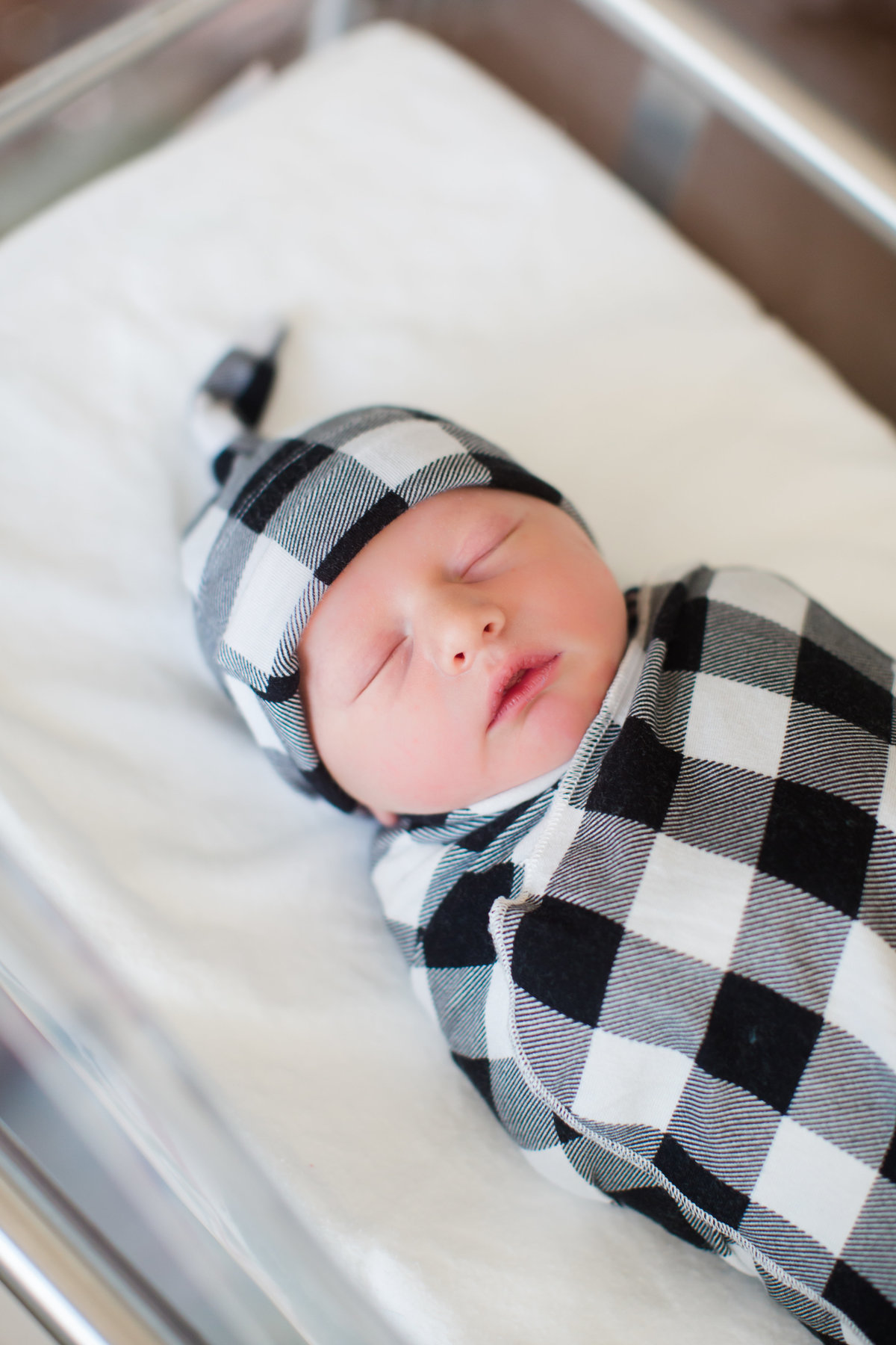 baby wrapped in black plaid swaddle at hospital for photos