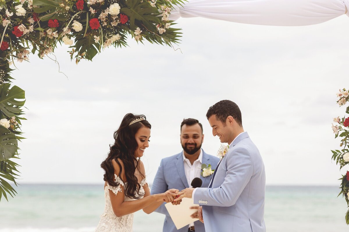 Bride putting ring on groom at wedding in Riviera Maya