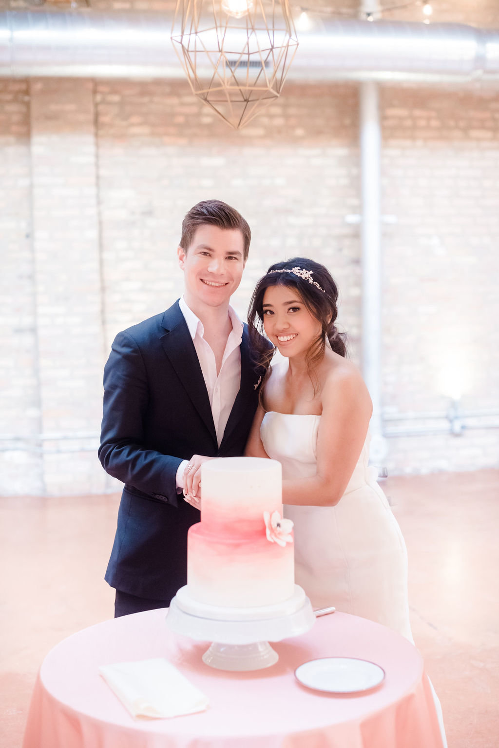 A smiling man and woman holding hands in front of their wedding cake
