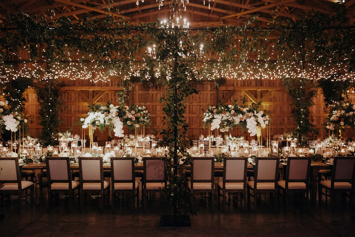 Elegant string lights over head table with tall flower centerpieces