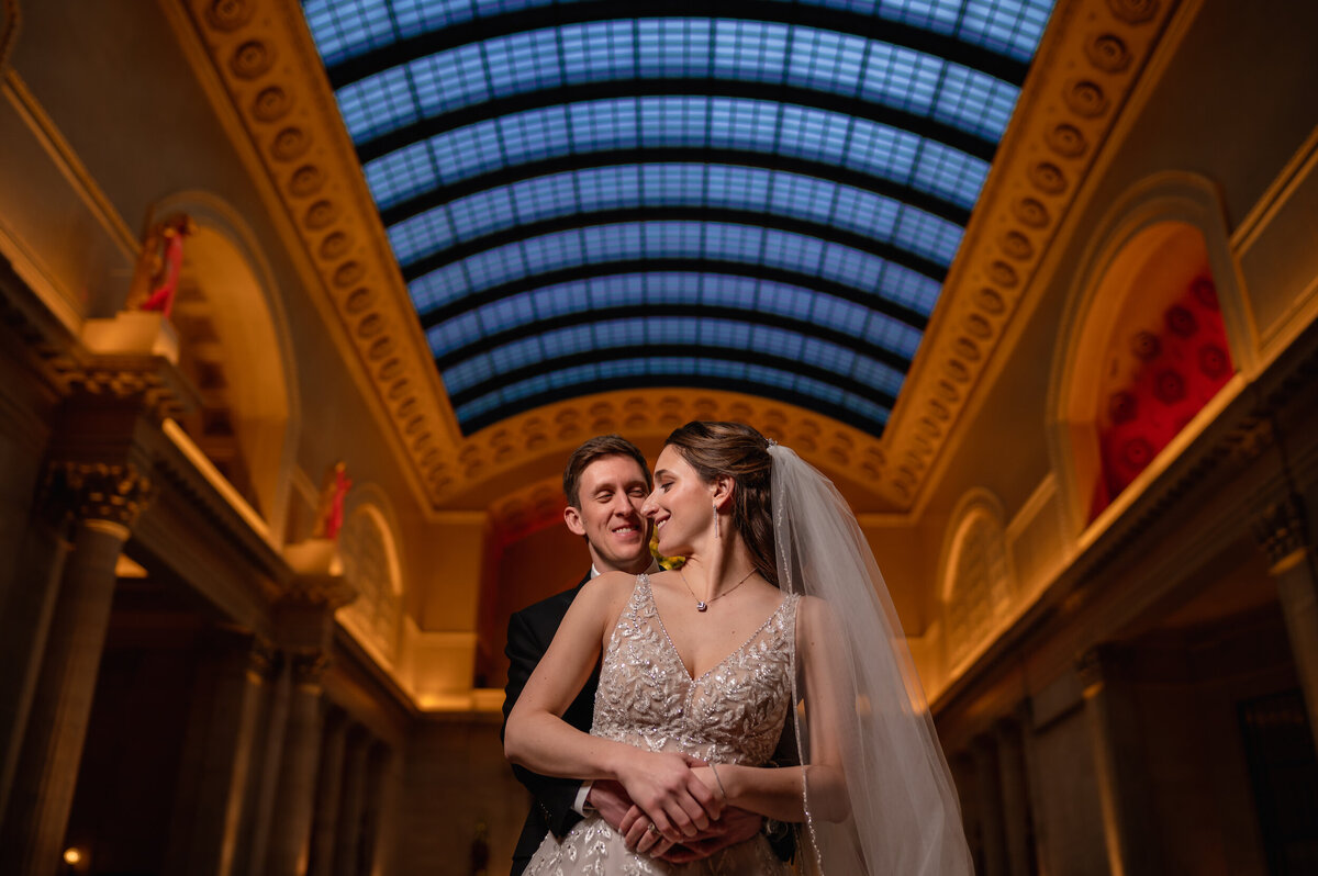 Bride and groom stand under a huge skyline at the Chicago Union Station