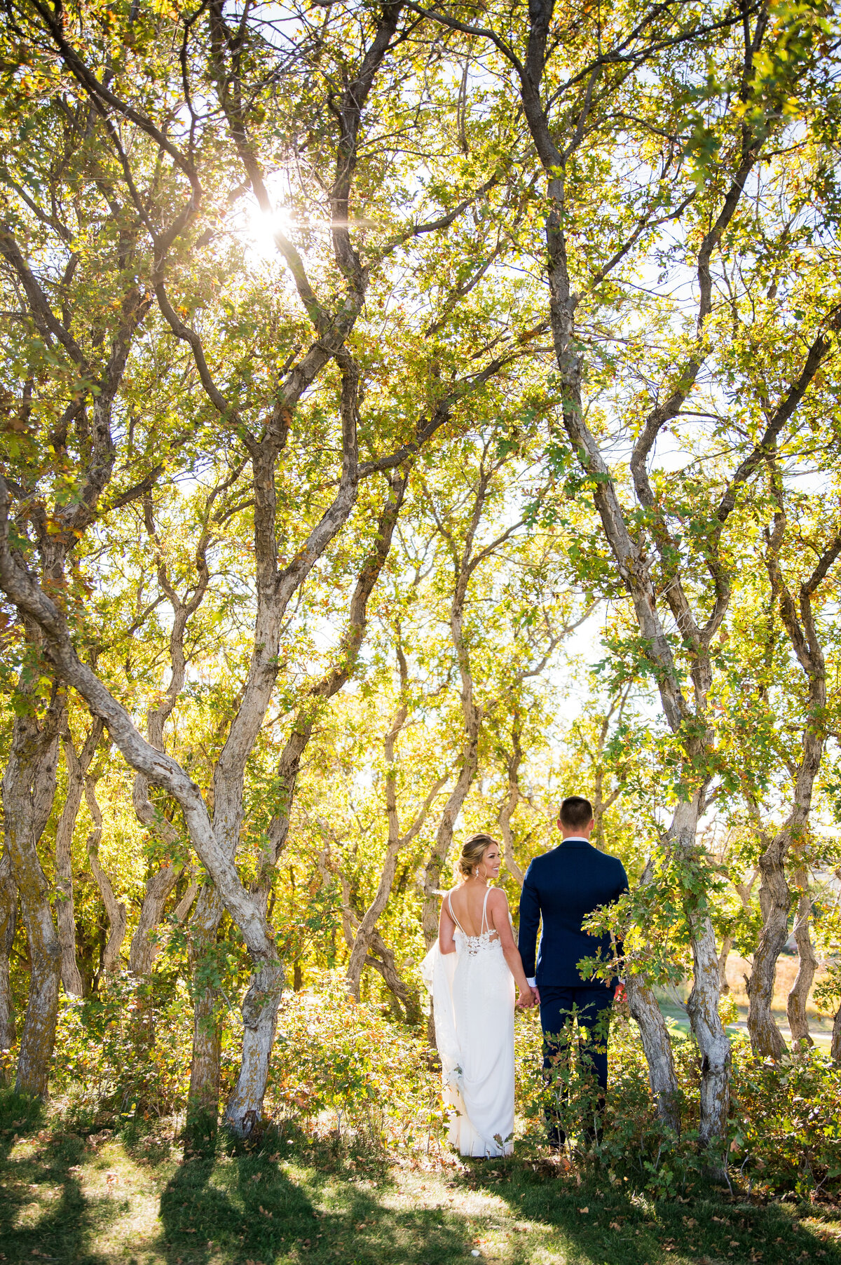 A bride and groom stand in the oak trees at The Oaks at Plum Creek and the bride looks up at her groom.