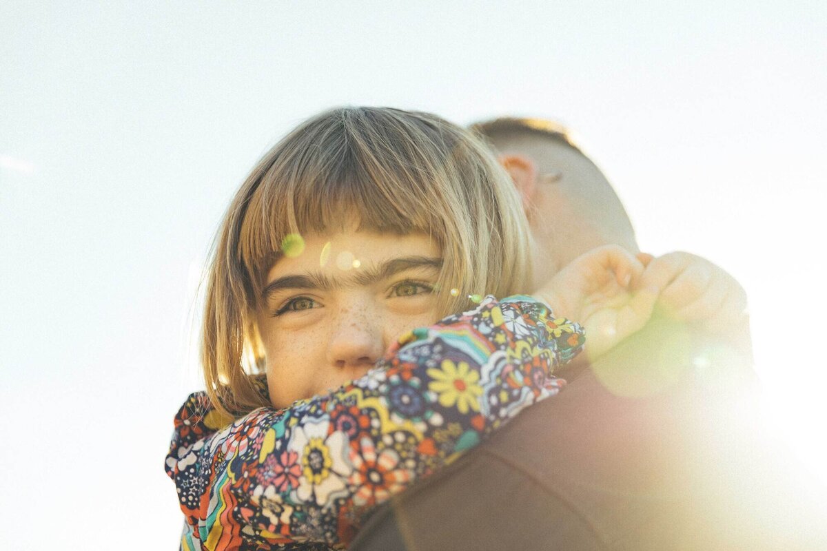 father hugging toddler daughter over his shoulder during a family photo session in san francsico.