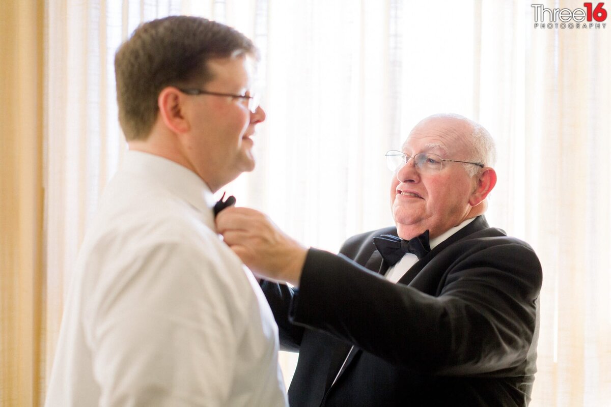 Groom's father straightens his bow tie