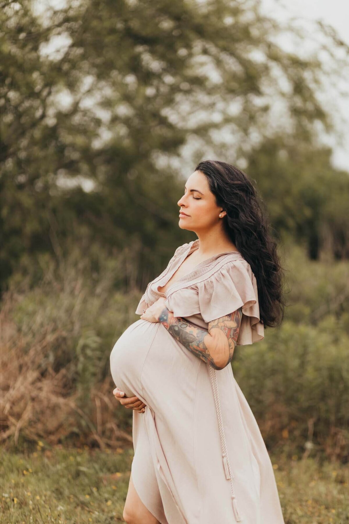 Ally's Photography captures expectant mother holding her belly wearing a neutral maternity flowy dress.