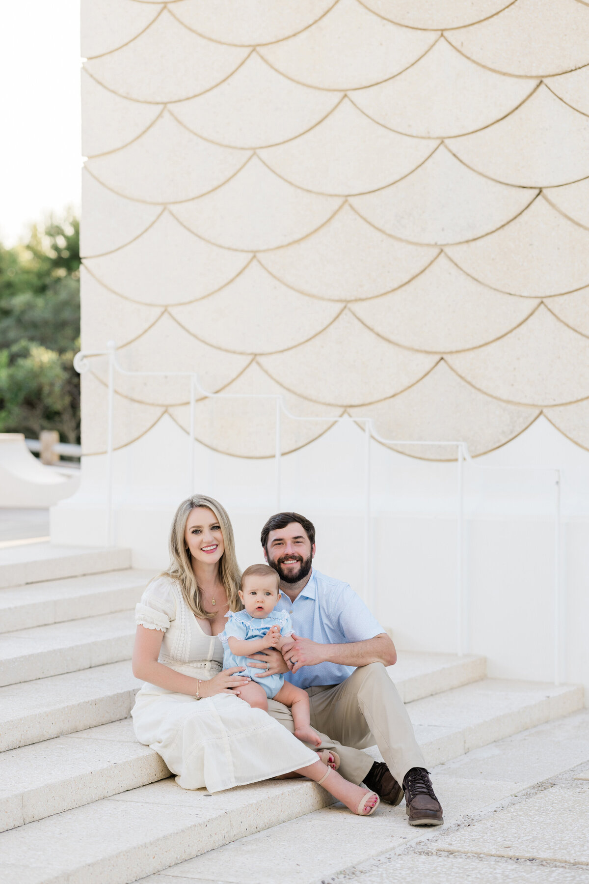 Two parents sitting on steps with a baby on their lap.