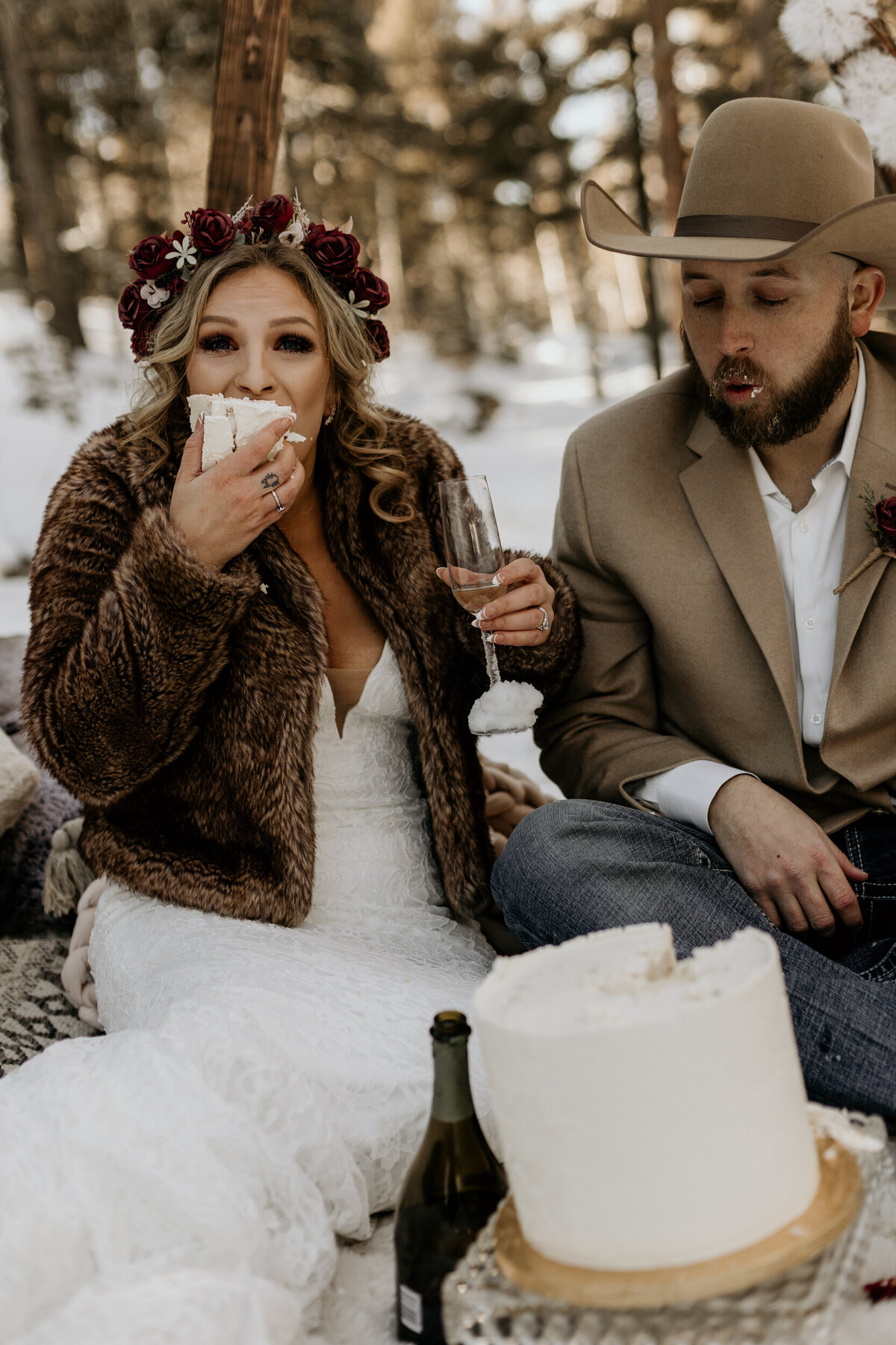 bride and groom eating their cake in the snow
