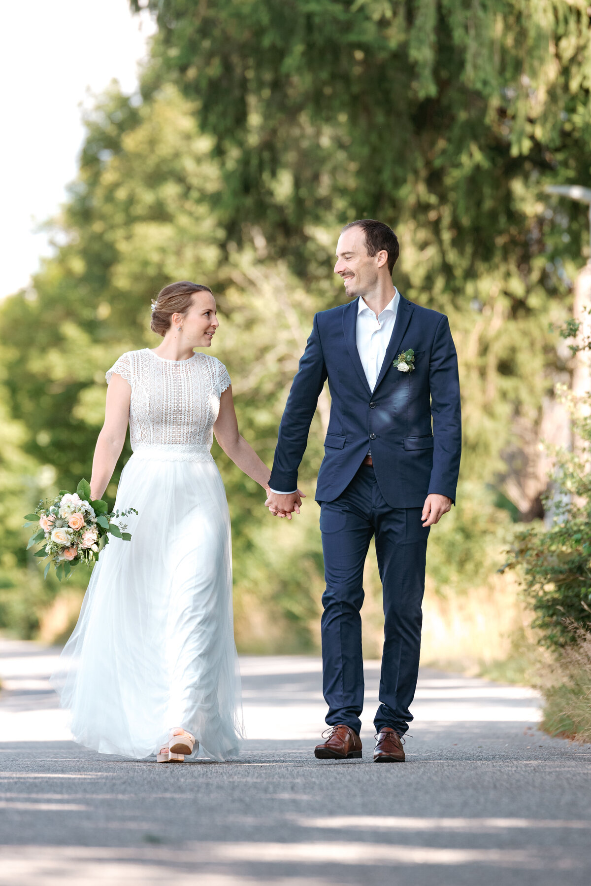 Brautpaar geht händchenhaltend einen Weg entlang hochzeitsfotograf Starnberg