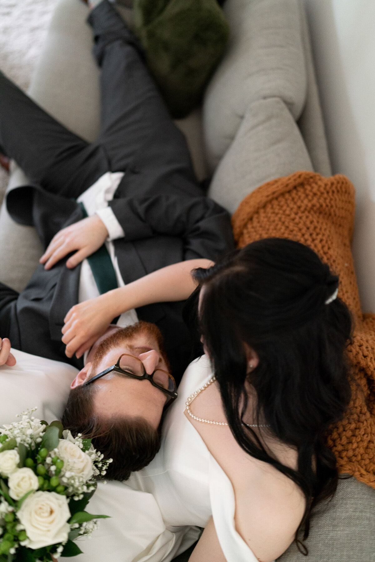 Bride and groom cuddle on the couch.