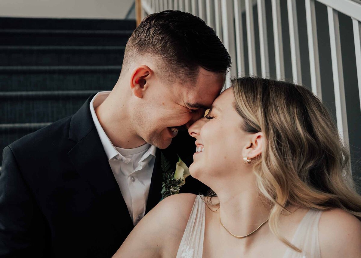 Maddie Rae Photography bride and groom sitting on stairs. they are touching foreheads smiling at each other. this is a close up shot