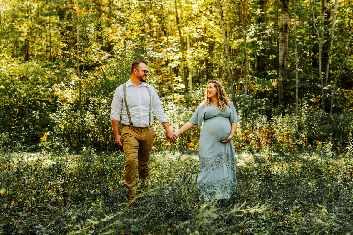maternity couple walking together in field