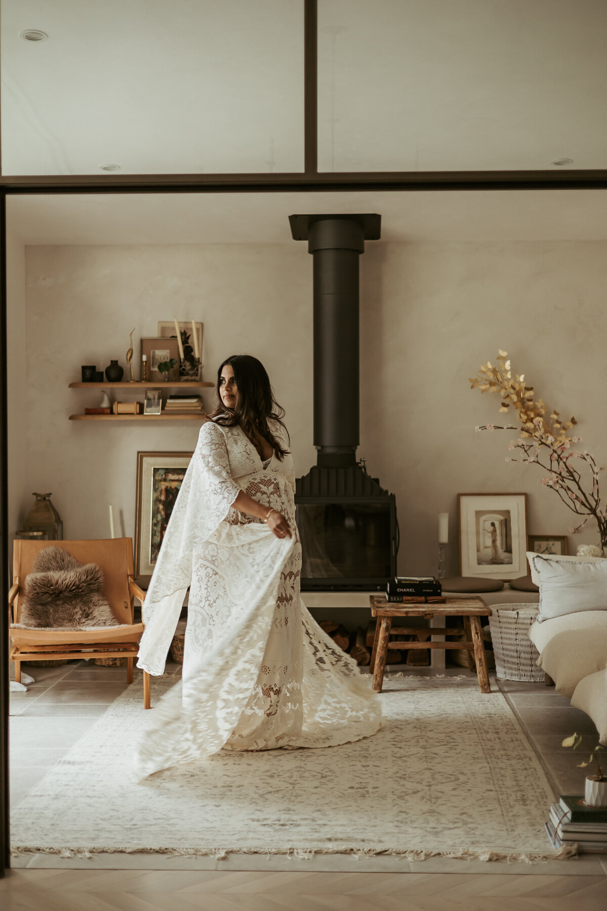 Beautiful mother to be in a gorgeous long white lace dress in her living room swishing her dress