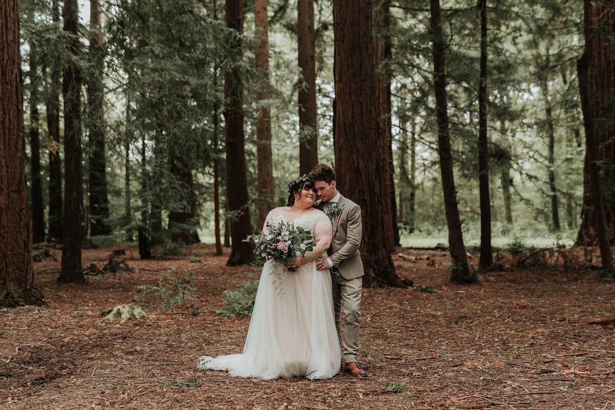Bride & Groom standing in the middle of beautiful woodlands at their romantic whimsical wedding at Two Woods Estate