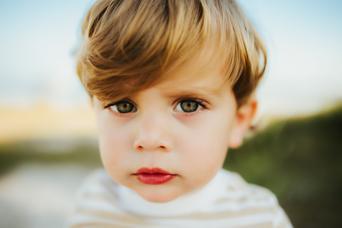 up close portrait of a toddler boy  outside at the beach looking directly at the camera