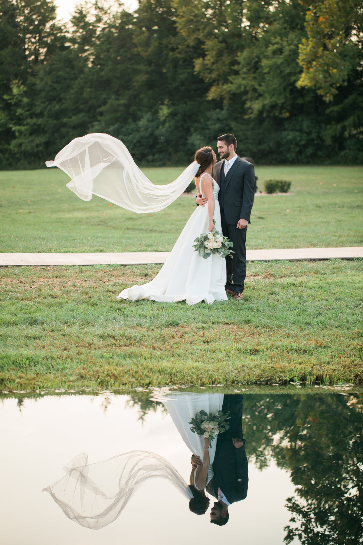 Reflection of bride and groom on lake.