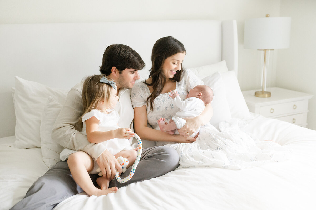 a family spending time together with their newborn on a white bed