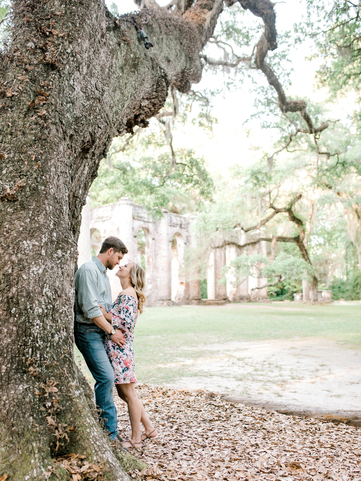 Couple leans on tree with church in background