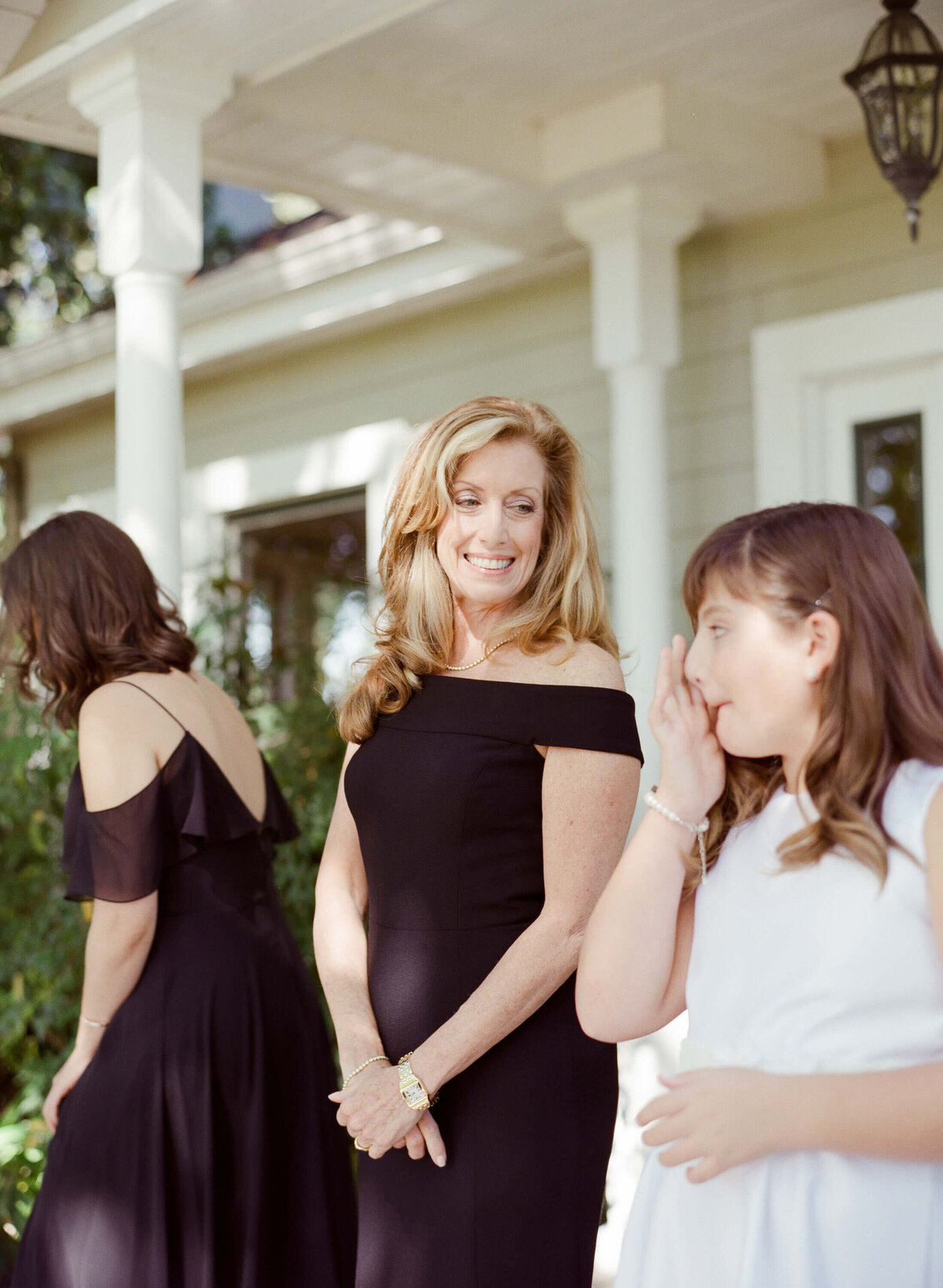 Preparations for a courtyard wedding in Wine Country are finally over as a bridesmaid watches a younger girl adjust her makeup.