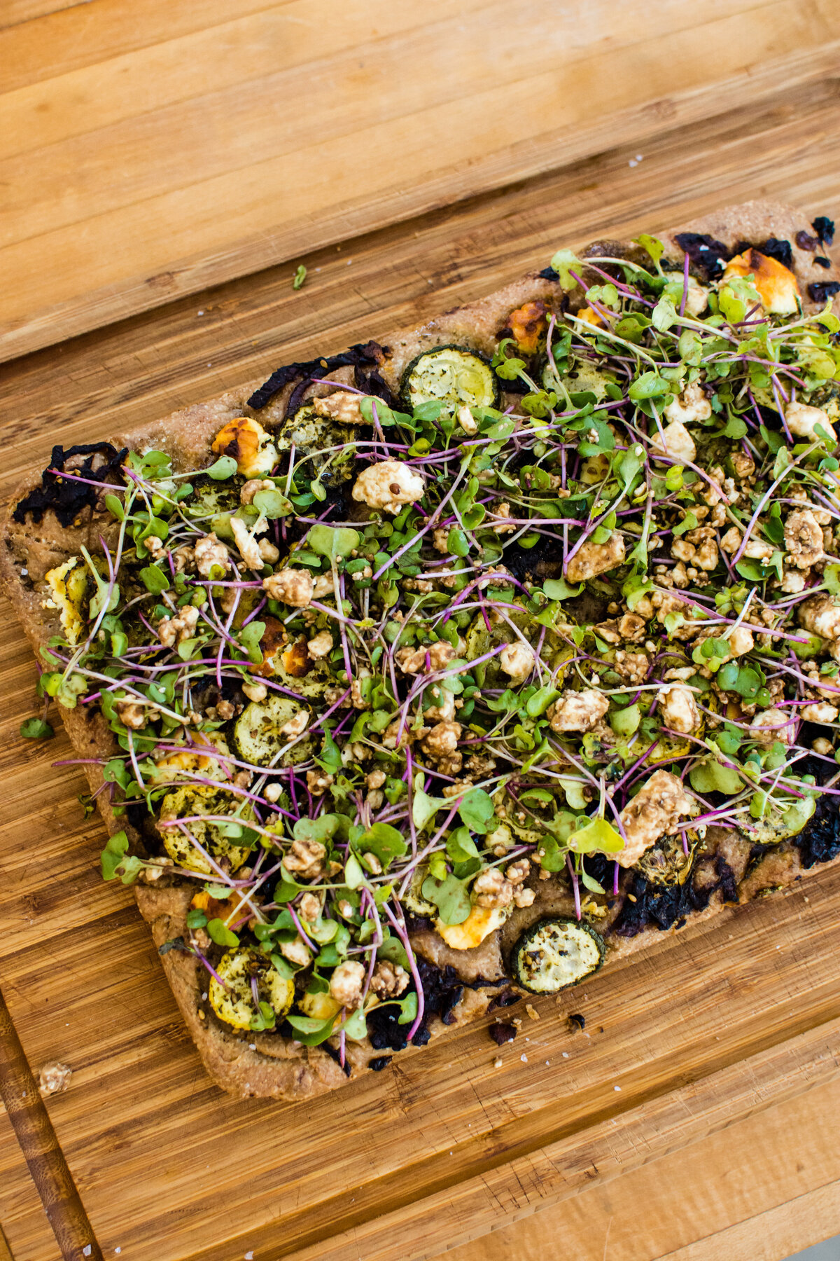 Overhead shot of savory focaccia with micro greens on a cutting board
