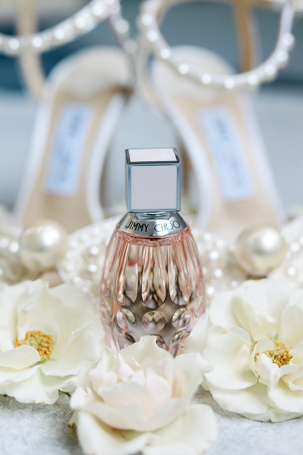 Luxurious Jimmy Choo perfume surrounded by white flowers, set against a backdrop for a December wedding at the Don Cesar Hotel, St. Pete Beach, FL.