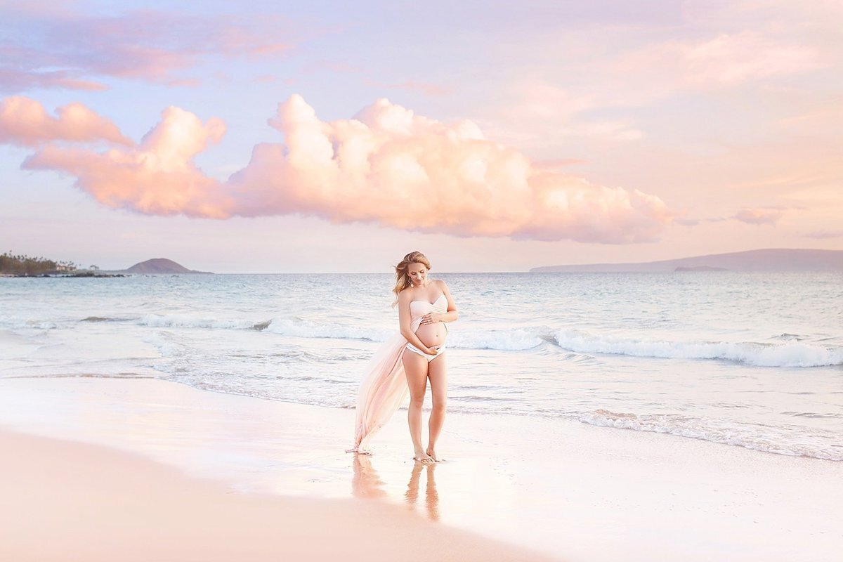 Beautiful pink tones surround a pregnant mother having her maternity photos taken by Love + Water Photography during her Maui babymoon