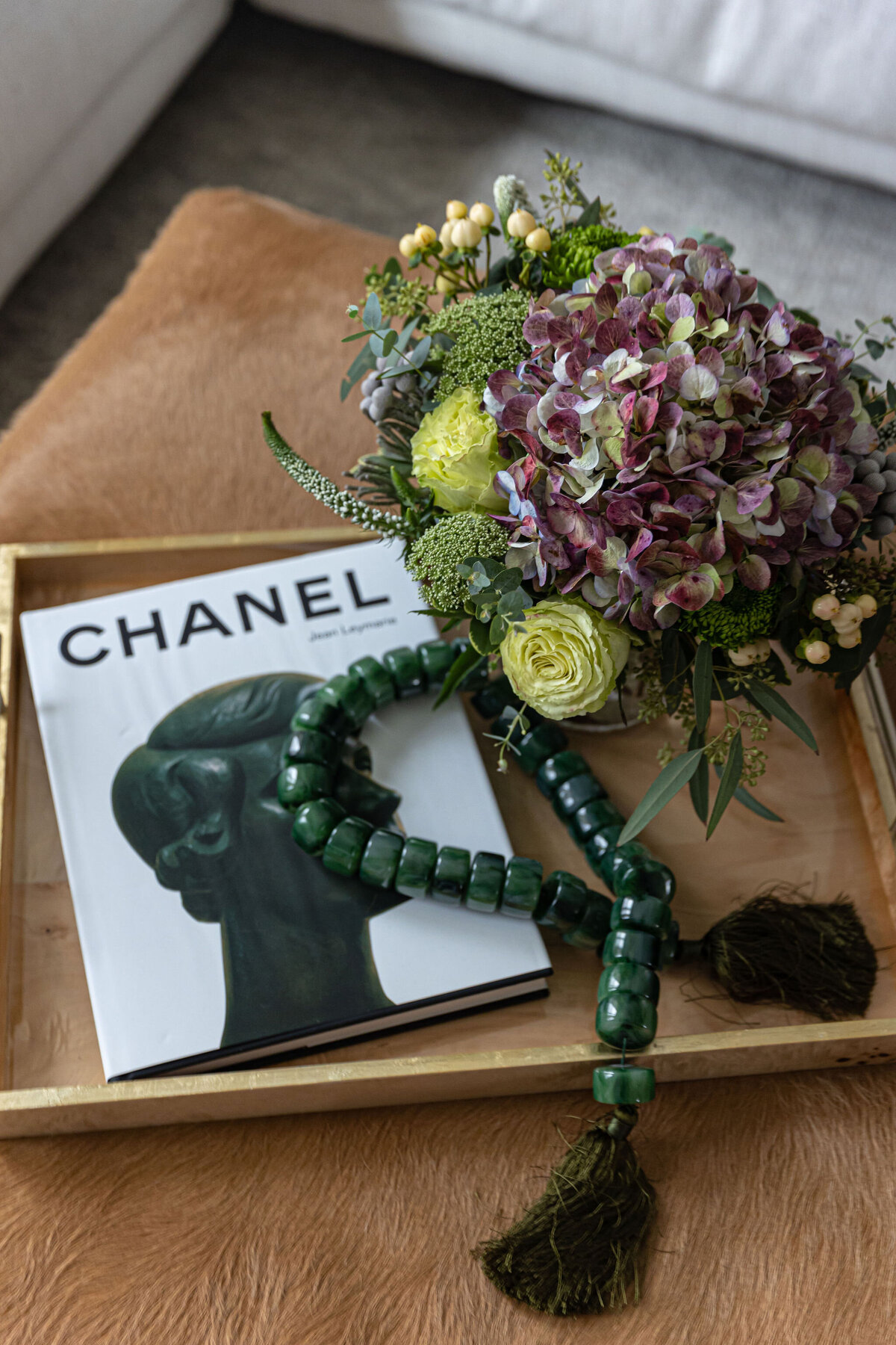 flowers, a book, and jewelry on a serving tray