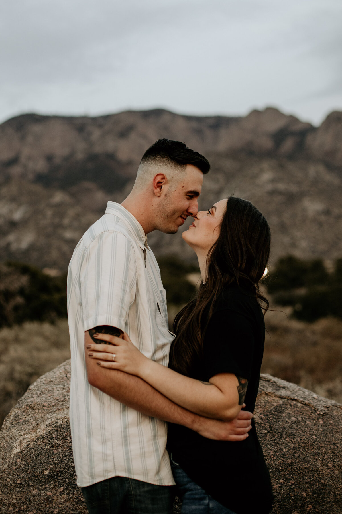 engaged couple about to kiss in front of the Sandia mountains
