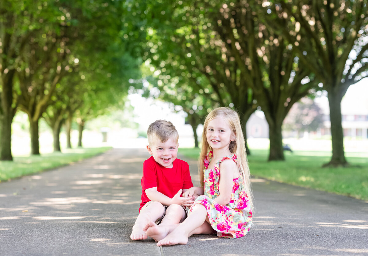 boy and girl siblings sitting on walkway