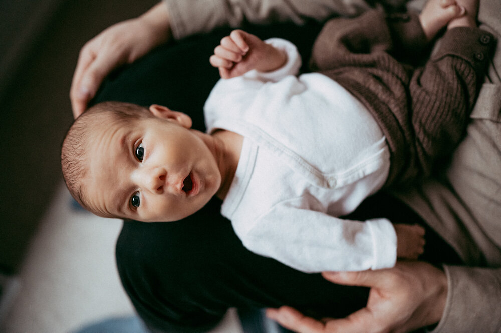 Newborn making an expressive face while resting in parent’s arms, captured in a candid moment during a relaxed, baby-led session in Portland.