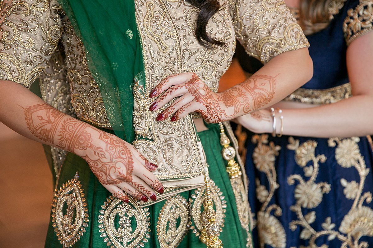 Sheikh bride displays her wedding henna mendhi while wearing a green and gold saree