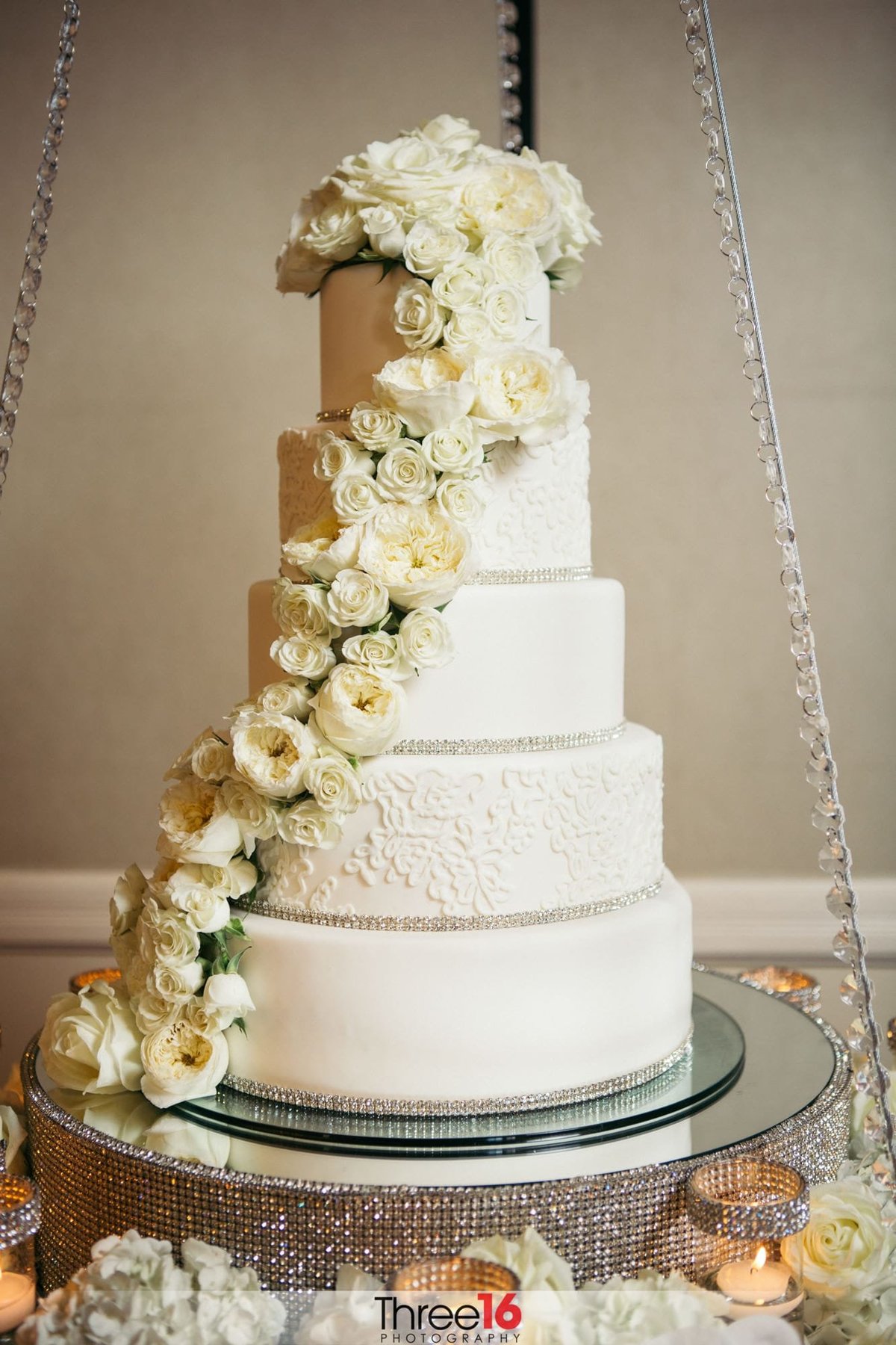 White 5-tiered wedding cake with flowers draped along the side