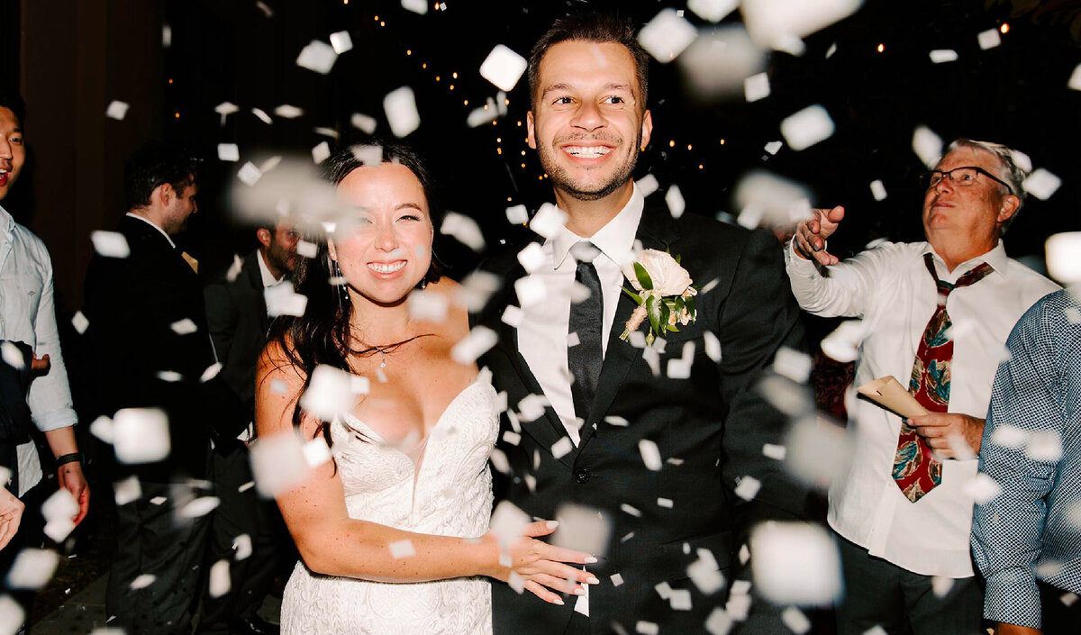 bride-and-groom-walking-while-party-throws-confetti