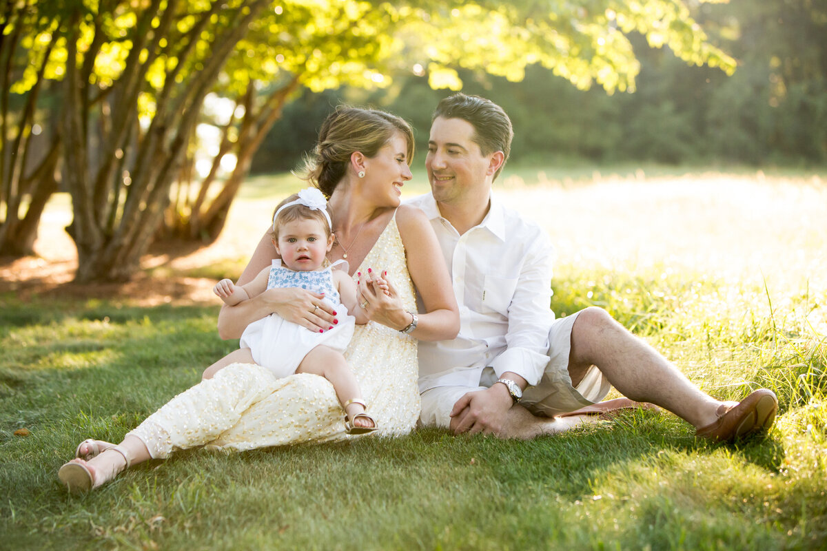 A mother in a yellow dress and her husband in a white shirt sit in the sunshine Hudson Valley family photographer Milestone Images