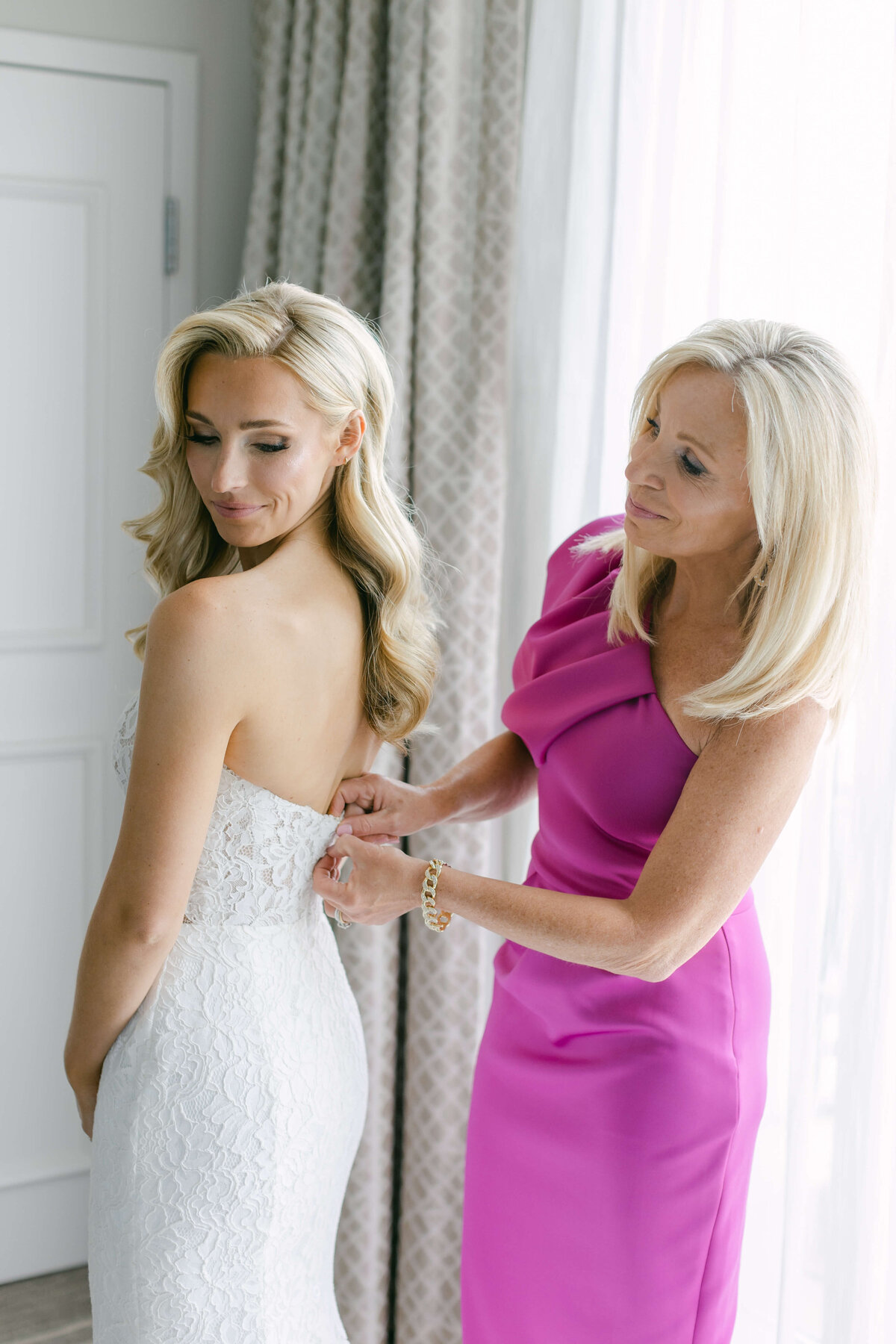 A mother helps her daughter into her wedding dress.