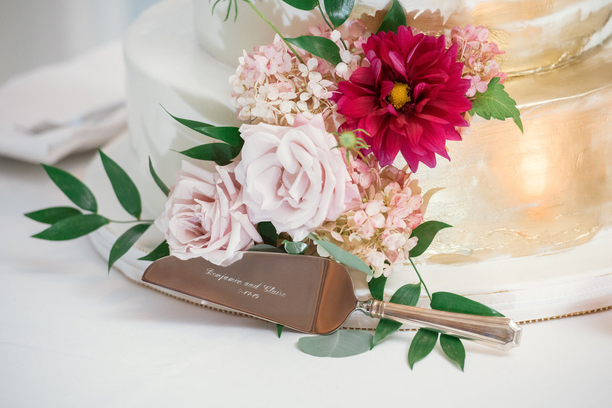 close up of engraved cake cutter with flowers and cake photo from wedding at The Muttontown Club