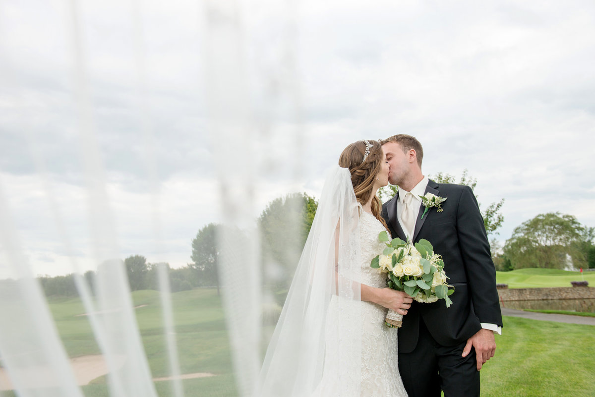 bride and groom kissing photo on the golf course at Willow Creek Golf and Country Club wedding photo
