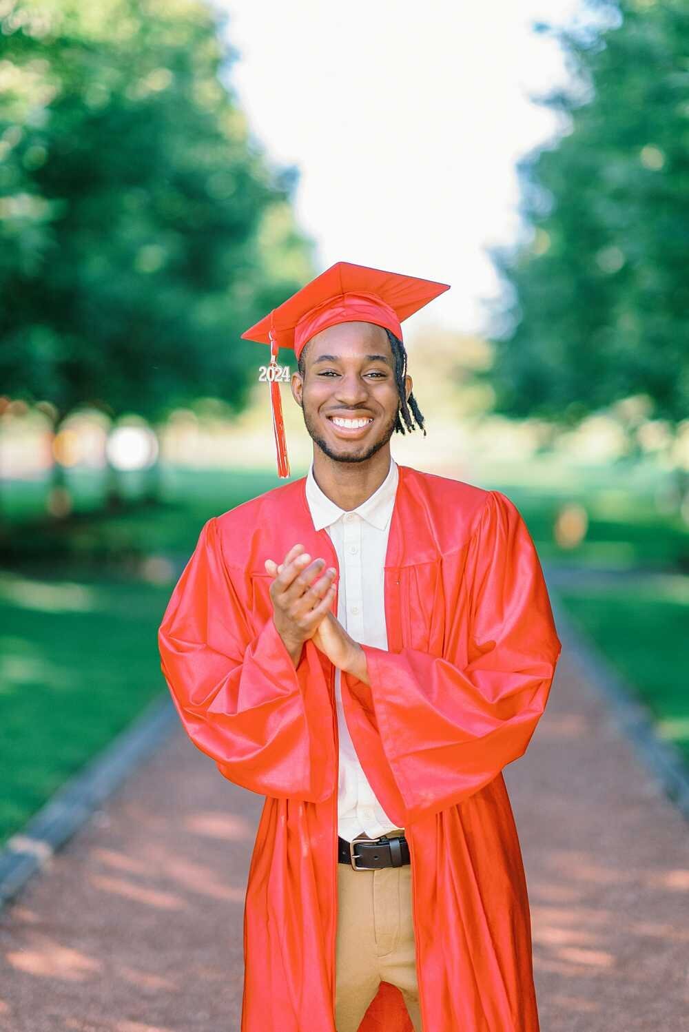 Senior guy wearing a cap and gown and rubbing his hands together