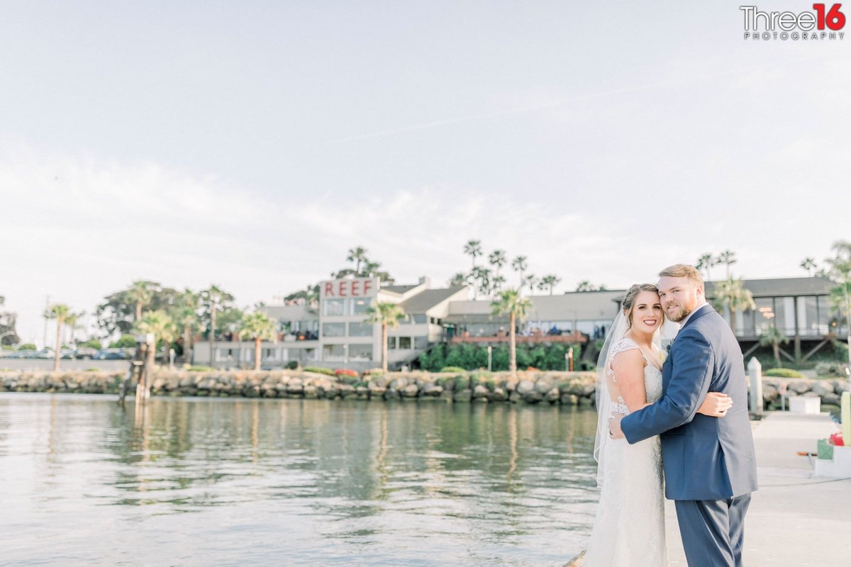 Bride and Groom embrace one another next to the Long Beach Harbor in front of The Reef