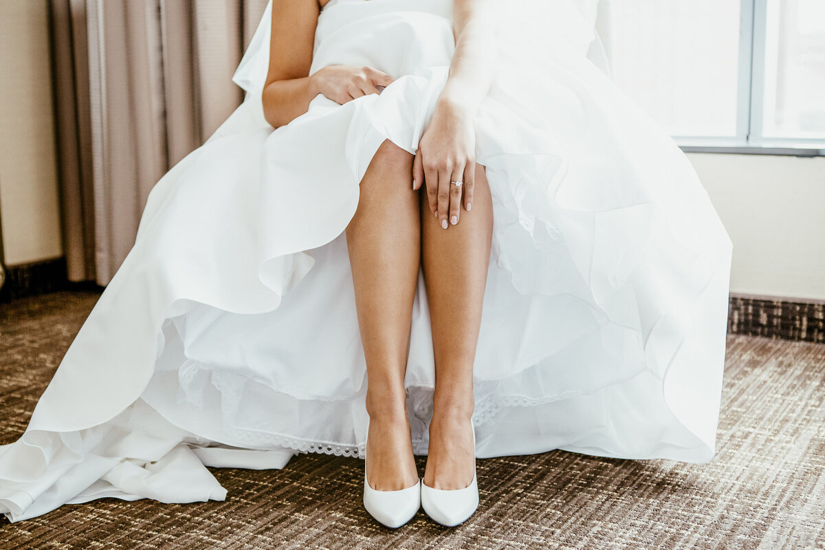 Bride sitting on a chair in her wedding dress and showing her engagement ring