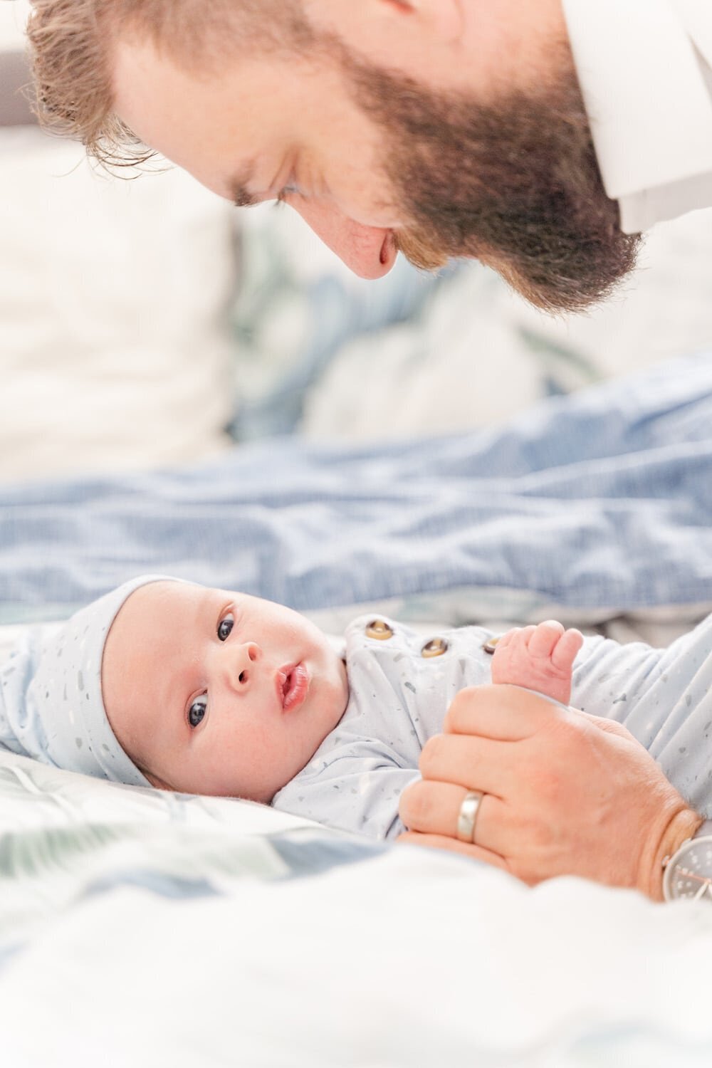 dad holding baby boy's hands during lifestyle newborn photography in Fairfax County, VA
