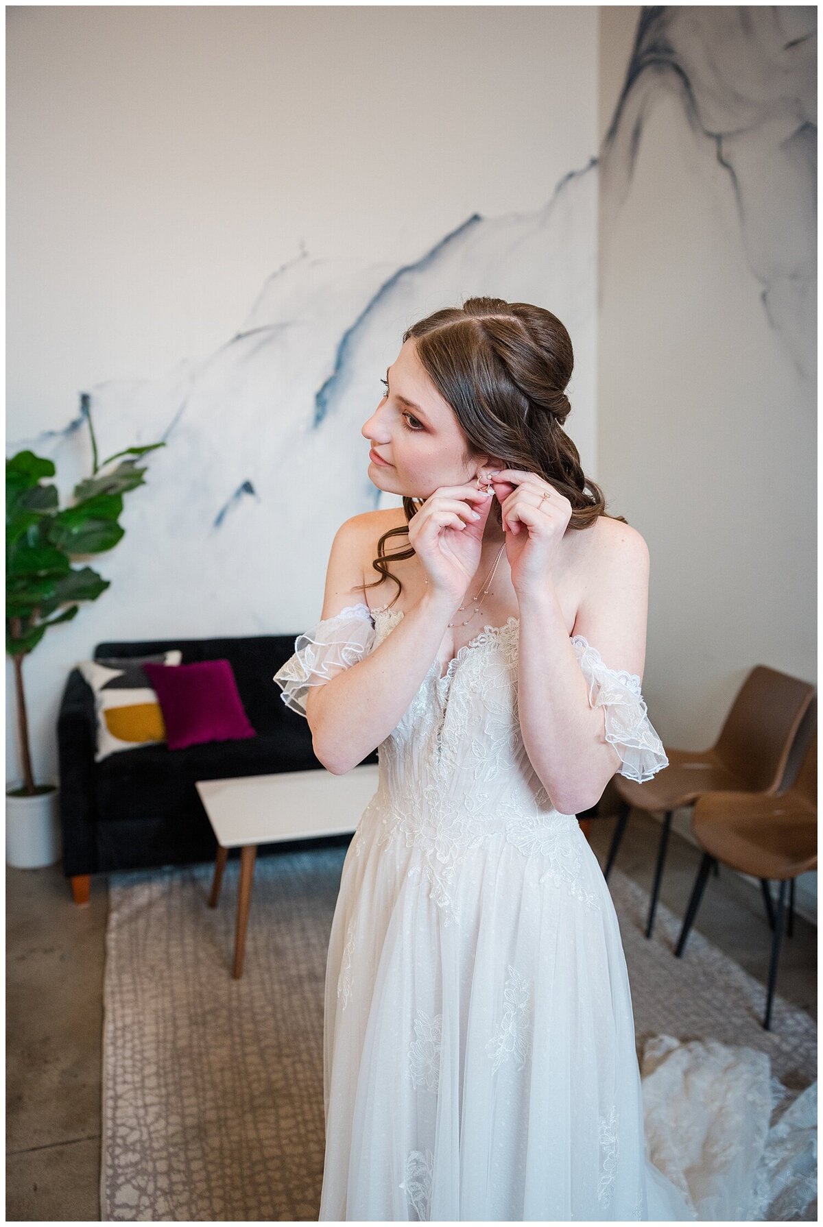 A detail shot from the waist up of a bride putting on her earrings in the bridal suite of Skylight in Denver