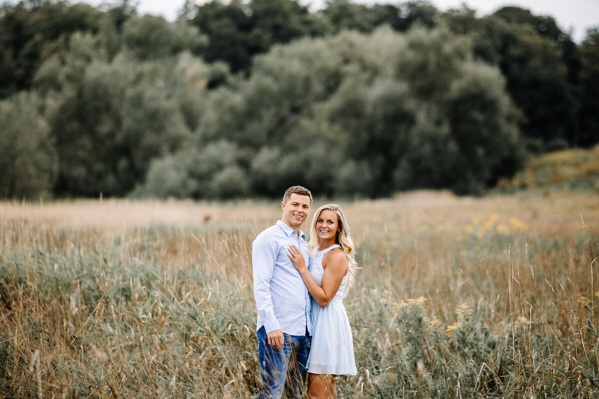 Engaged couple embracing in field in Buffalo, New York