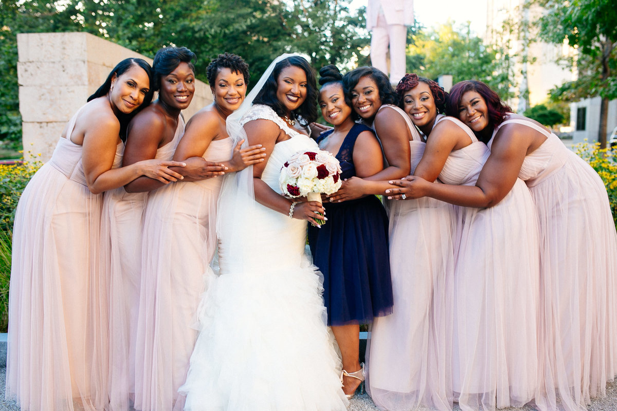 Bride and bridesmaids, dressed in pink and navy, pose outside the Caramel Room in St. Louis