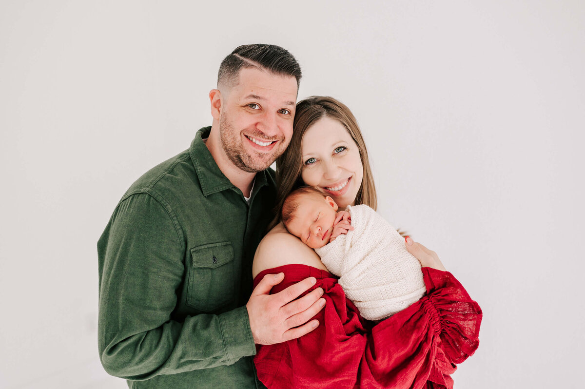 family smiling with sleeping newborn in Springfield MO newborn photography studio