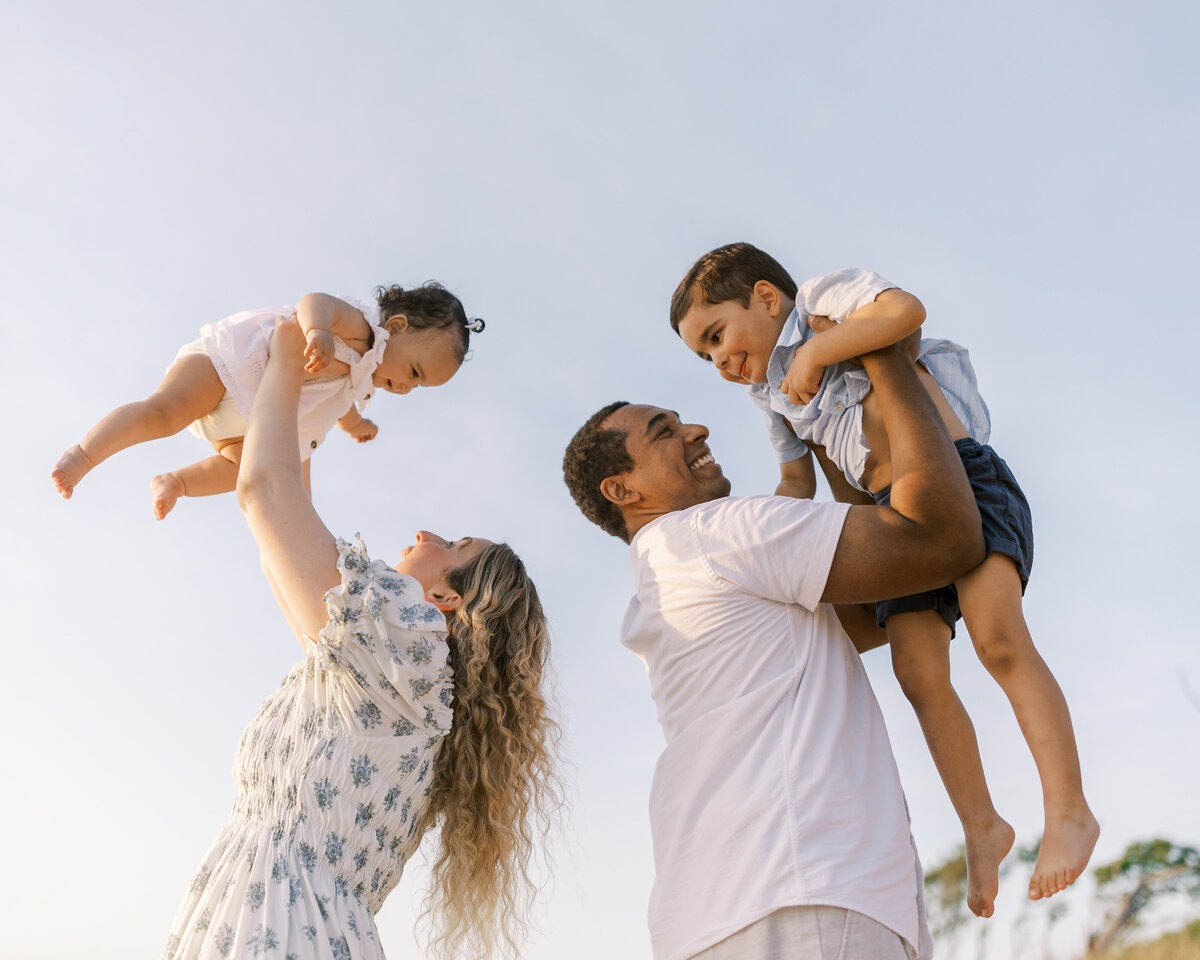 Parents toss their young children in the air during beach family photography session