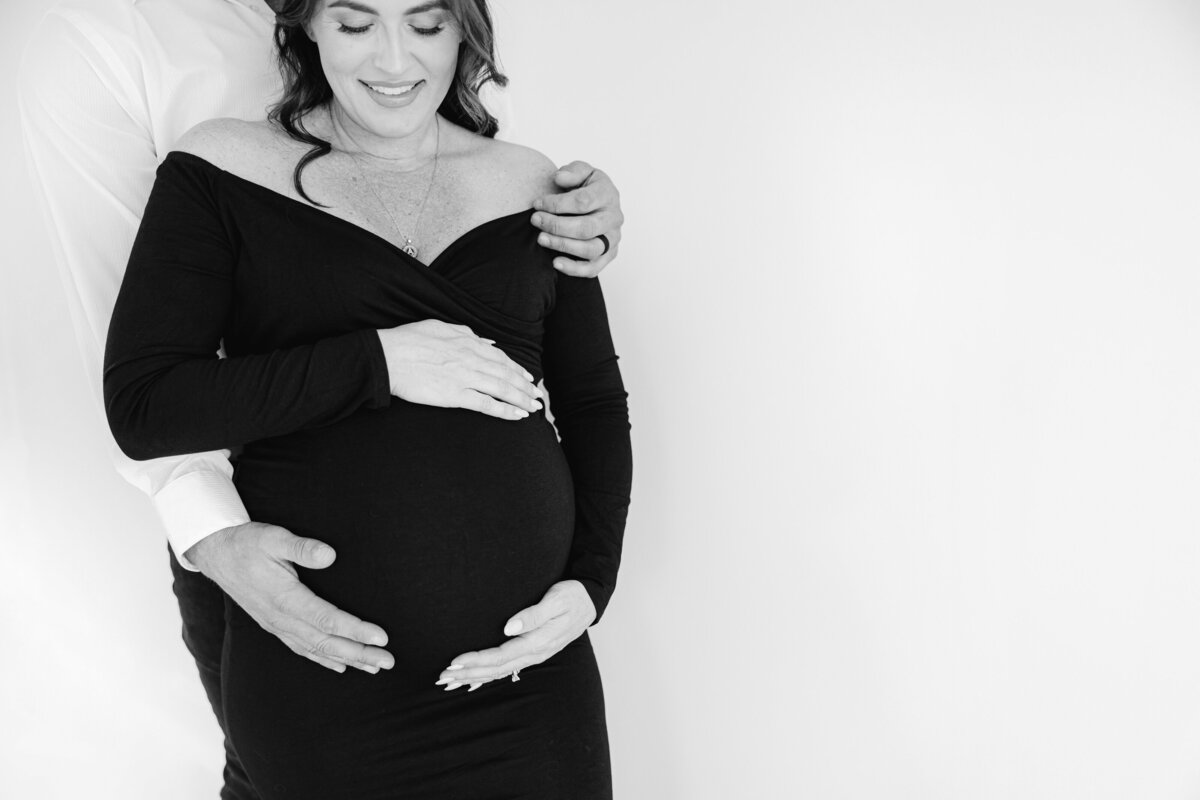 black and white photo of mom and dad with hands on belly