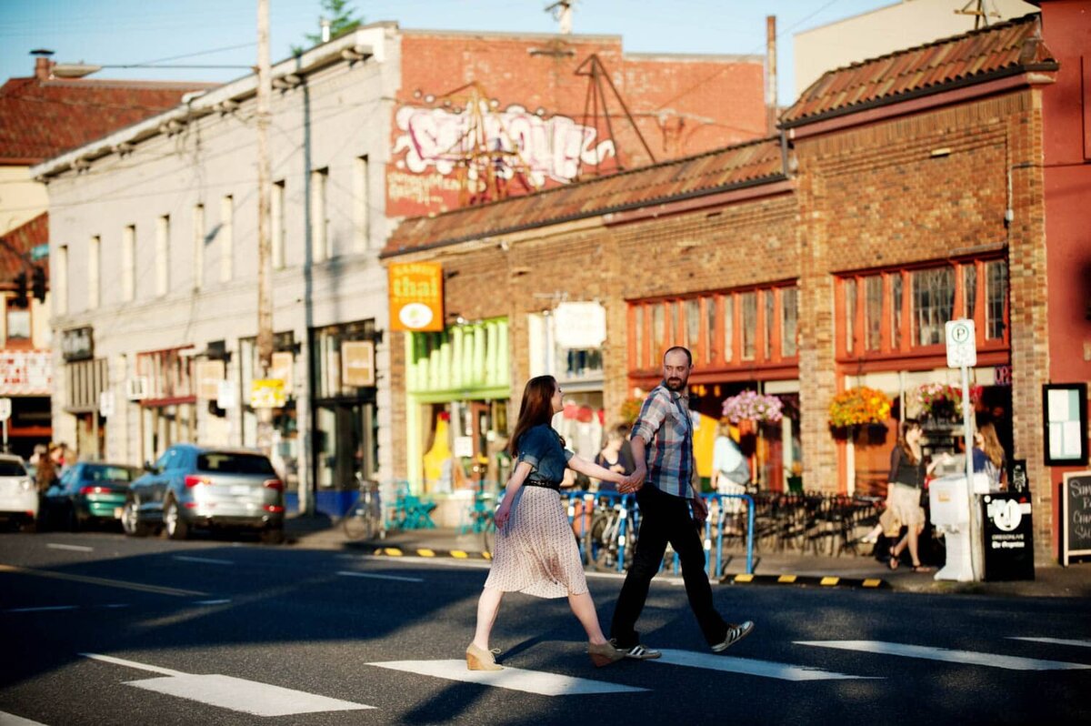 a man pulls a woman by her hand across a crosswalk on hawthorne blvd in portland